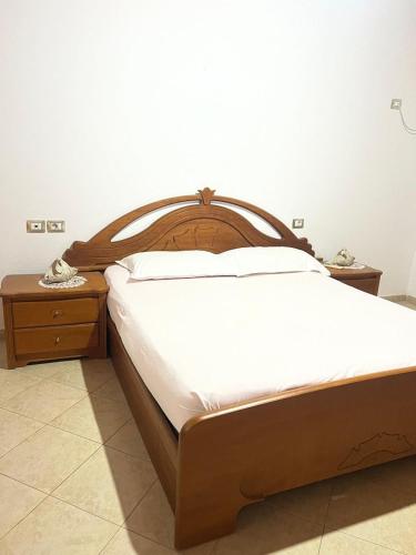 a bedroom with a wooden bed and two night stands at Nori House in Vlorë