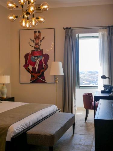 a bedroom with a bed and a desk and a chandelier at Battery House in Valletta