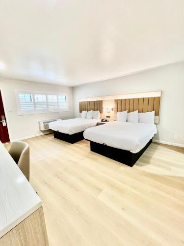 two beds in a large room with wooden floors at Nob Hill Motor Inn -Newly Updated Rooms! in San Francisco