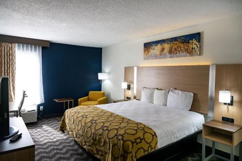 a hotel room with a large bed and a chair at Baymont by Wyndham Greensboro/Coliseum in Greensboro