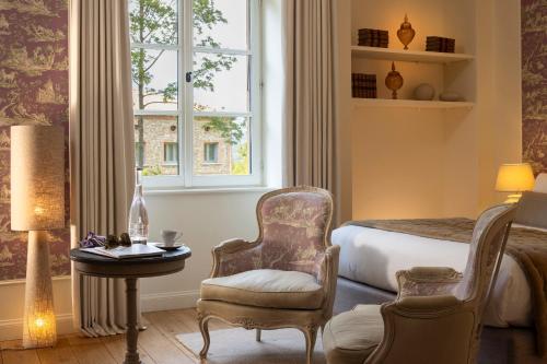 a bedroom with a bed and a chair and a table at Château Les Oliviers de Salettes in Charols