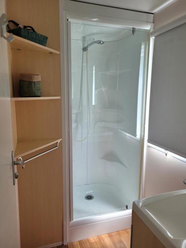 a shower with a glass door in a bathroom at Bungalow cosy pour 6 personnes in Ivry-la-Bataille