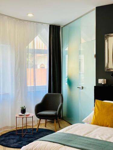 een slaapkamer met een bed, een stoel en een raam bij Studio apartman in Kőszeg