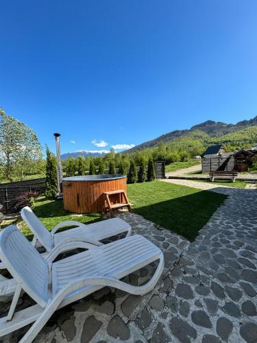 two white lounge chairs sitting on a patio at Green Hill Resort in Zărneşti