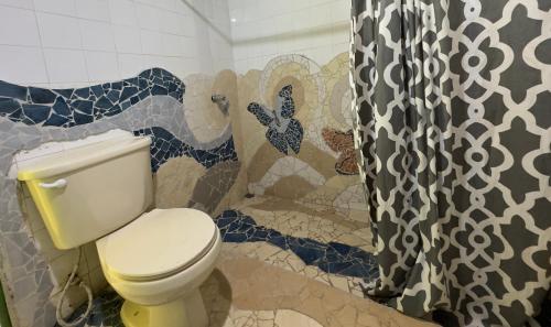 a bathroom with a toilet and a shower curtain at Casa Mamré in Cahuita