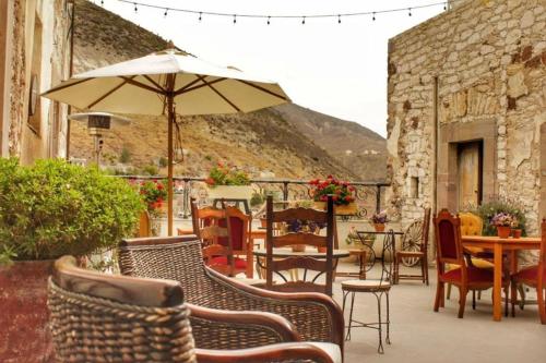 eine Terrasse mit Stühlen, Tischen und einem Sonnenschirm in der Unterkunft Casa Grande - Adults Only in Real de Catorce