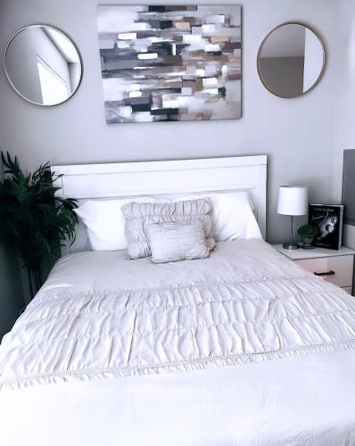a bedroom with a white bed with two mirrors at Downtown Luxury Studio in Dallas