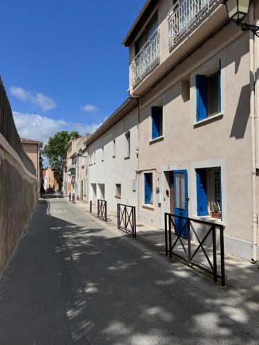 pusta ulica z białym budynkiem z niebieskimi oknami w obiekcie La Mouette Bleue maison de ville individuelle w mieście Martigues