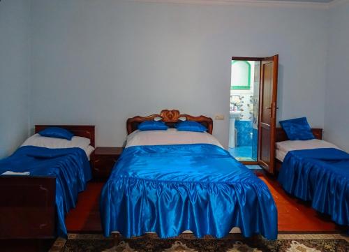 a bedroom with two beds with blue sheets at Aspet B&B in Tatʼev