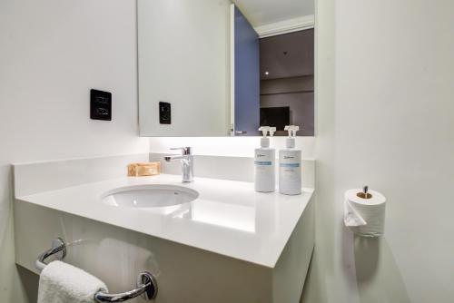 a white bathroom with a sink and a mirror at Radisson São Paulo Paulista in Sao Paulo