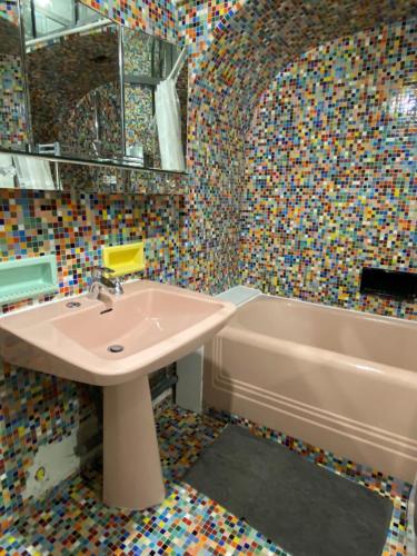 a bathroom with a sink and a tub with mosaic tiles at L'appartement des Champs Elysées in Paris
