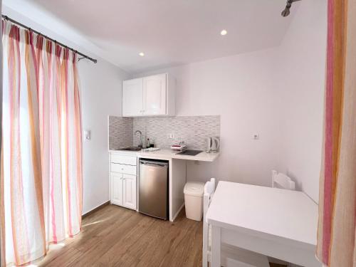 a small kitchen with white cabinets and a table at Cyclades Blue in Ornos