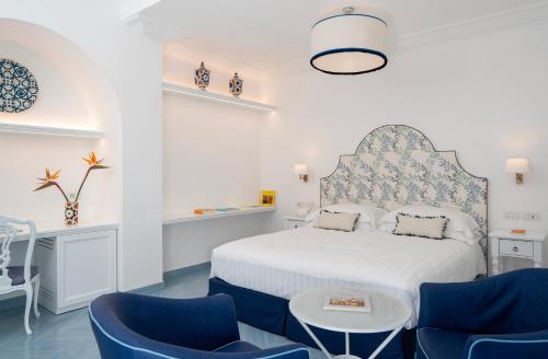 a white bedroom with blue chairs and a bed at Boutique Hotel Casa Mariantonia in Anacapri