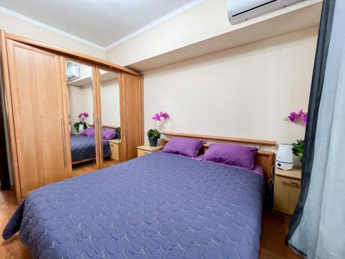 um quarto com uma cama roxa e um espelho em Золотой квадрат 60 кв2 em Almaty