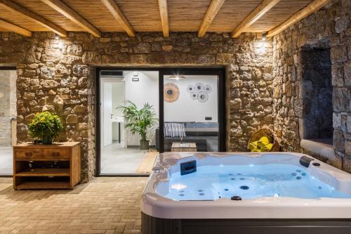 a jacuzzi tub in a room with a stone wall at Mykonos Cottage in Ano Mera