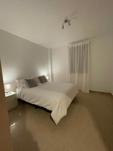 a white bedroom with a bed and a window at Disfruta Jerez in Jerez de la Frontera