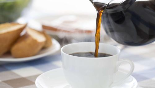 a person is pouring coffee into a cup on a table at Magnuson Hotel Sand Springs – Tulsa West in Sand Springs
