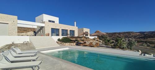 a swimming pool with chairs and a house at Komos Beach Estate in Kalamaki Heraklion