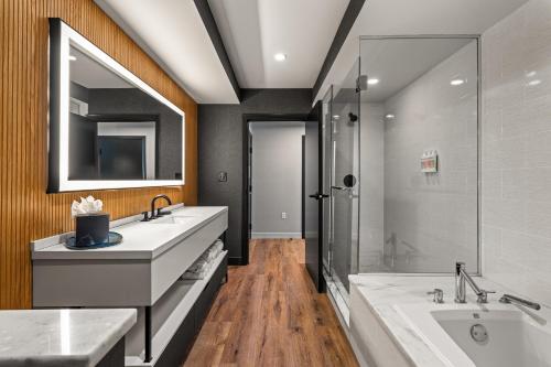 uma casa de banho com 2 lavatórios, uma banheira e um chuveiro em The Watershed - Formerly Hotel Zero Degrees em Norwalk