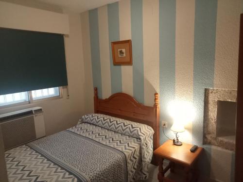 Dormitorio pequeño con cama y mesa con lámpara en Hostal Trujillo, en Trujillo