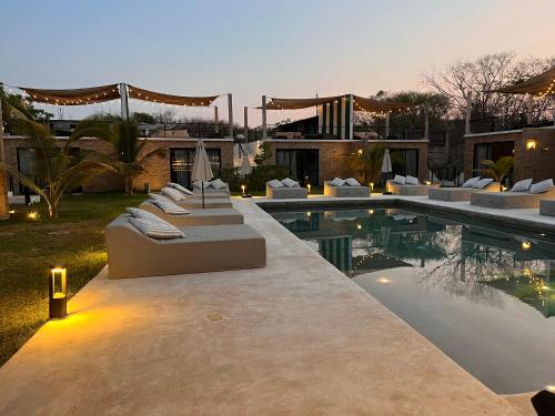 a pool with couches and chairs next to a house at Bora Boutique - Adults Only in Puerto Escondido