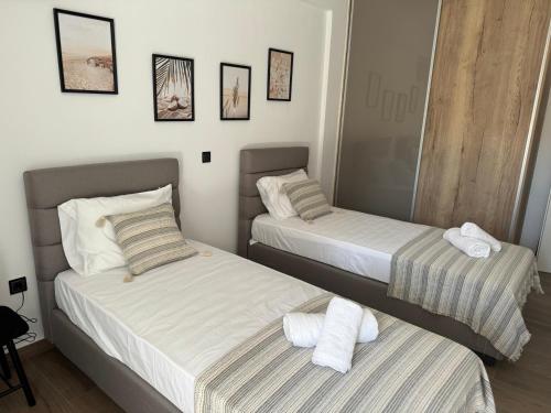 two beds in a hotel room with towels at Villa Achilleas by the sea in Anavissos