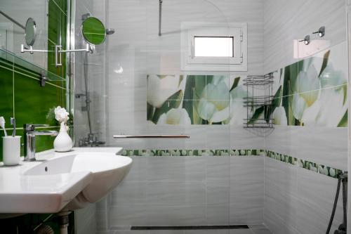 Un baño blanco con lavabo y espejo. en B&G Beach bliss apartment, en Nea Iraklia