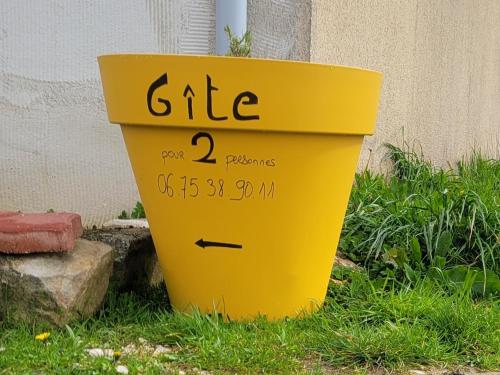 a yellow trash can sitting in the grass at À la campagne in Yèvres