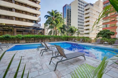 a swimming pool with lounge chairs next to a building at Radisson São Paulo Paulista in Sao Paulo