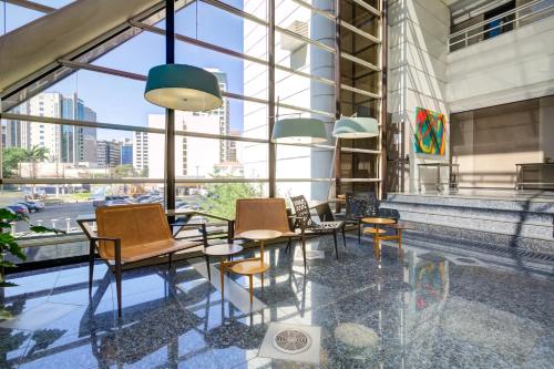 a group of chairs and tables in a building with windows at Radisson São Paulo Paulista in Sao Paulo