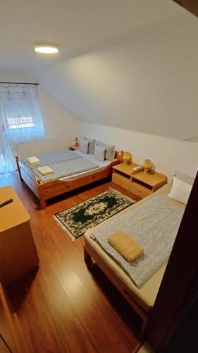 two beds in a room with wooden floors at Ágica Vendégház in Andornaktálya