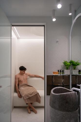 a man sitting in a bath tub in a bathroom at Lagon Life Spirit Boutique Hotel - Adults Only in Chania Town