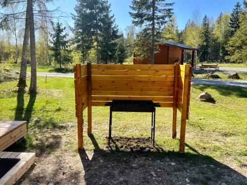 eine Holzbank im Gras in einem Park in der Unterkunft Marika Puhkeküla - Metsanurga Öömaja "shared bathroom" in Nõva