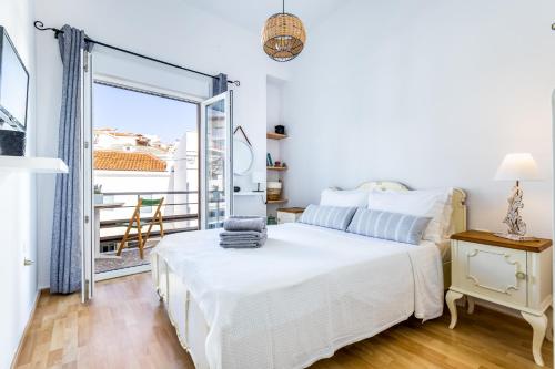 a white bedroom with a bed and a balcony at Iria's Petite Apartment in Skopelos Town