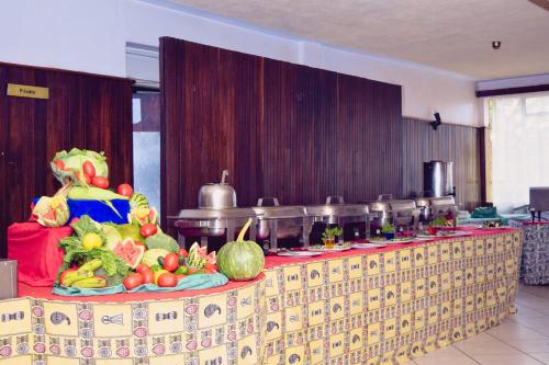 une table avec des fruits et des légumes en plus dans l'établissement Garden Hotel Machakos, à Machakos