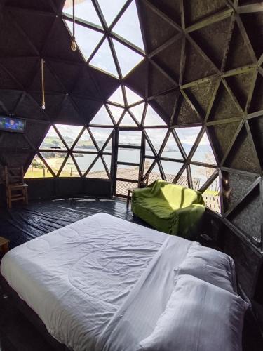 a bed in a room with a large window at GLAMPING PLAYA BLANCA in Tota