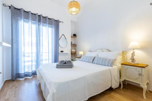 a white bedroom with two beds and a window at Iria's Petite Apartment in Skopelos Town