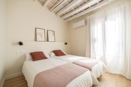 1 dormitorio blanco con 2 camas y ventana en Casa con historia en el centro. en Castellón de la Plana