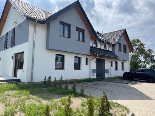 a white house with a car parked in the driveway at Apartamenty Parkowe in Łęknica