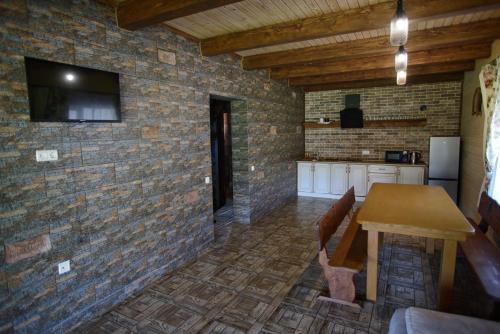 a kitchen with a table and a tv on a brick wall at Еміліана in Volosyanka