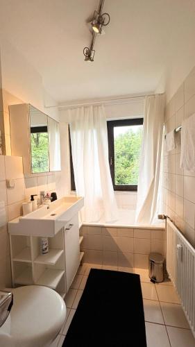 La salle de bains blanche est pourvue d'un lavabo et d'une fenêtre. dans l'établissement Charmant hell citynah, à Wiesbaden