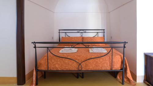 uma cama com uma estrutura de metal preto e almofadas cor-de-laranja em Vineyard View, Garden & Barbecue - Authentic "Dammusi" em Pantelleria