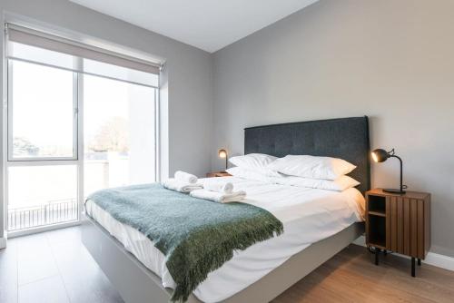 een witte slaapkamer met een groot bed met een groene deken bij Woodward Square One by Dublin At Home in Dublin