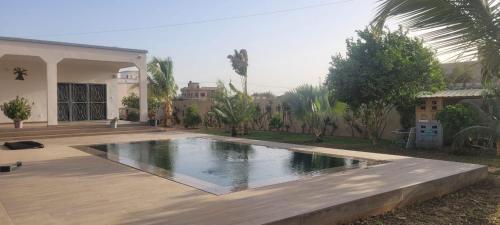 a swimming pool in front of a house at Keur Aïda in Malikounda Sas