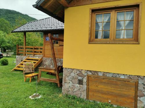 une maison jaune avec une fenêtre et un bâtiment dans l'établissement Wooden House Ripac, à Bihać