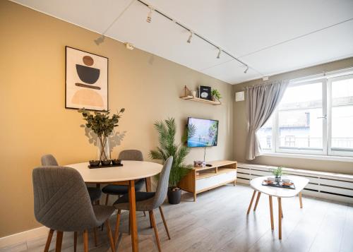 sala de estar con mesa, sillas y TV en Ultracentral duplex with private rooftop terrace, en Oslo