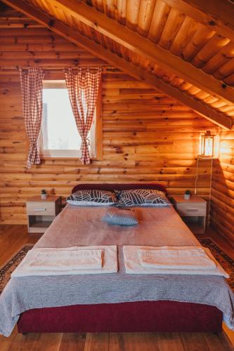 a bedroom with a large bed in a log cabin at Kuča za odmor Stina in Slavetić