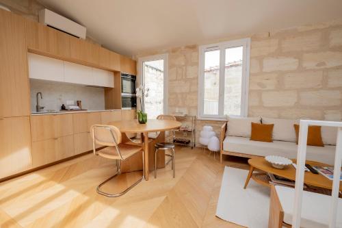 une cuisine et un salon avec une table et un canapé dans l'établissement Appartement cosy au cœur des chartrons, à Bordeaux