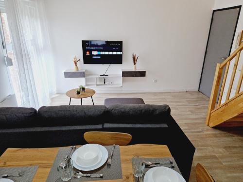a living room with a black couch and a tv at AU BON PLAN in Maubeuge
