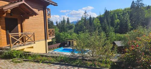 a house with a swimming pool next to a building at Barvy Karpat in Slavske